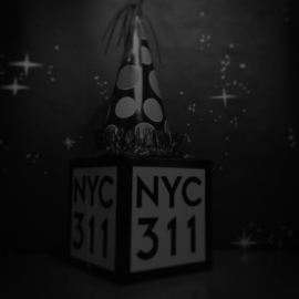 Photo of a cube object with each side reading 'NYC 311'